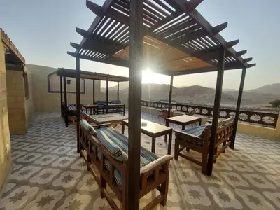 a pavilion with benches and tables and a view of the mountains at Carter Guesthouse Luxor 1 in ‘Ezbet Abu Ḥabashi