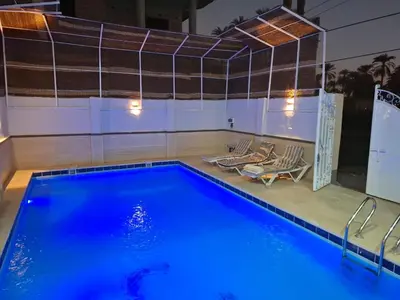 a swimming pool with two chairs next to a swimming pool at Djorff Guest House in Luxor