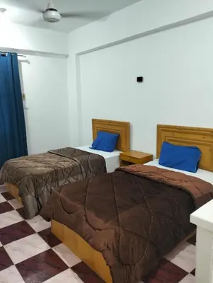 two beds in a hotel room with blue pillows at Djorff Guest House in Luxor