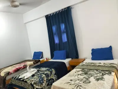 a room with two beds with blue pillows and a window at Djorff Guest House in Luxor