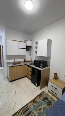 a kitchen with white cabinets and a black appliances at Cosy Hurghada Apartments in Hurghada