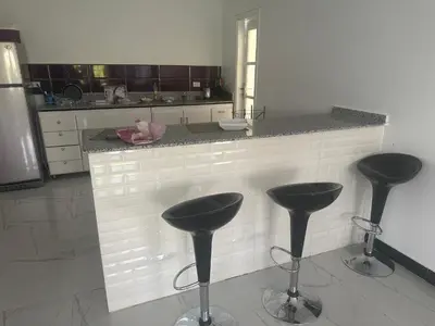 a kitchen with three bar stools in front of a counter at King mou in ‘Ezbet Abu Ḥabashi