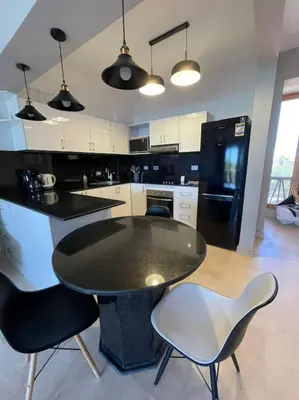 a kitchen with a table and chairs and a black refrigerator at The Sunset Heaven - 2 bedrooms - Golf Steigenberger, El Gouna in Hurghada