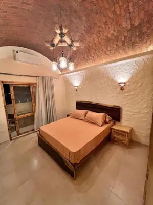 a bedroom with a bed and a brick wall at Komfortowy apartament na dachu w sercu miasta in Hurghada