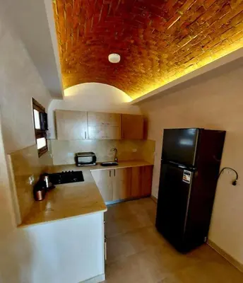 a kitchen with a black refrigerator and wooden cabinets at Komfortowy apartament na dachu w sercu miasta in Hurghada
