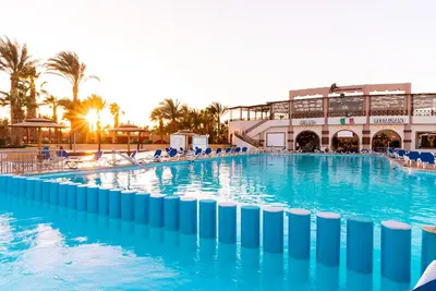 a large swimming pool with blue water in front of a building at Aladdin Beach Resort in Hurghada