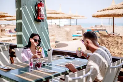 a man and a woman sitting at a table with drinks at Aladdin Beach Resort in Hurghada