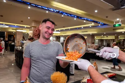 a man holding a plate of food in a store at Aladdin Beach Resort in Hurghada