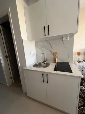 a kitchen with white cabinets and a sink at Chic Studio with Modern Comforts in Hurghada