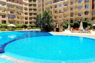 a large blue swimming pool in front of a large apartment building at Chic Studio with Modern Comforts in Hurghada