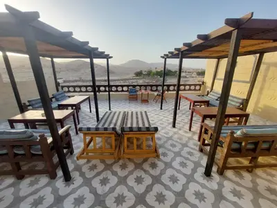 a patio with tables and benches on a roof at Carter Guesthouse Luxor 3 in Al Karnak