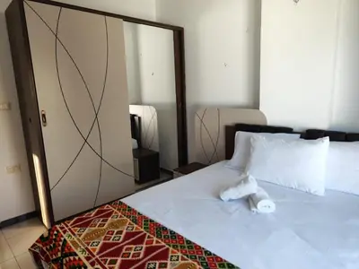 a bedroom with a large white bed with a mirror at Almina Apartments - Come and relax with us in style in Hurghada