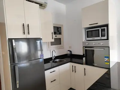 a kitchen with white cabinets and a stainless steel refrigerator at Almina Apartments - Come and relax with us in style in Hurghada