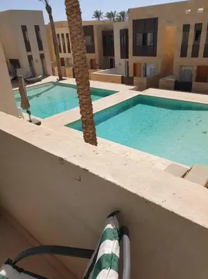 a swimming pool with a palm tree next to a building at Serene Pool View 8Mins to Marina in Hurghada