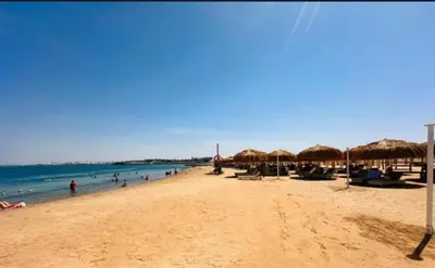 a beach with umbrellas and people in the water at Princess resort luxury A109 in Hurghada