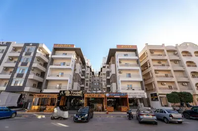 two tall buildings with cars parked in a parking lot at Hurghada apartment luxury 002 in Hurghada