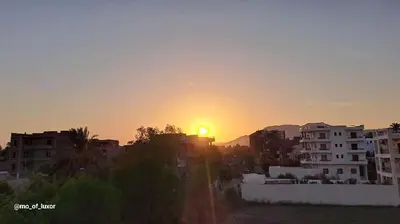a sunset over a city with buildings and the sun at Al Hayat house in Luxor