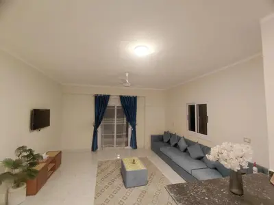 a living room with a blue couch and a tv at Al Hayat house in Luxor