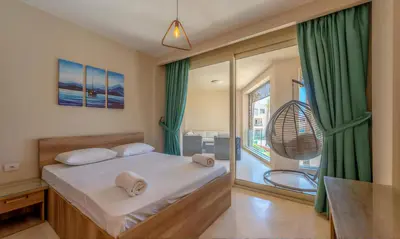 a bedroom with a bed with green curtains and a balcony at Luxury Stays in Mangroovy El Gouna in Hurghada
