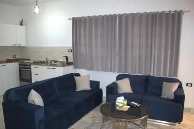 a living room with two blue couches and a table at AL Farida Guest House in Jazīrat al ‘Awwāmīyah