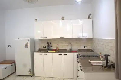 a kitchen with white cabinets and a white refrigerator at AL Farida Guest House in Jazīrat al ‘Awwāmīyah