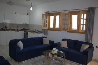 a living room with two blue couches and a table at AL Farida Guest House in Jazīrat al ‘Awwāmīyah