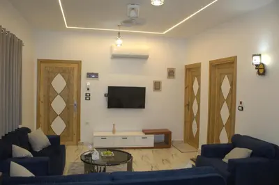 a living room with two blue couches and a tv at AL Farida Guest House in Jazīrat al ‘Awwāmīyah