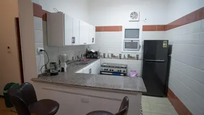 a kitchen with a black refrigerator and white cabinets at hodhod luxor in Al Qurnah