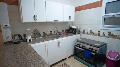 a kitchen with white cabinets and a sink and a stove at hodhod luxor in Al Qurnah