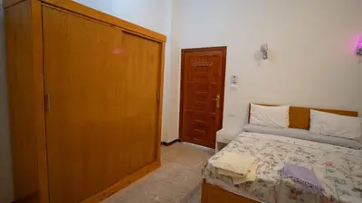 a bedroom with a bed and a wooden closet at hodhod luxor in Al Qurnah