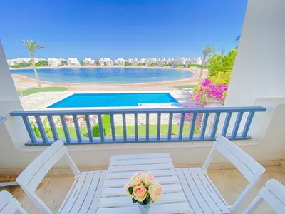 a balcony with a table and a view of a swimming pool at Nayah Stays, Joubal Lagoons flowery apartment in Hurghada