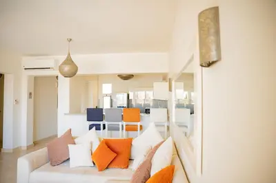 a living room with a white couch with colorful pillows at Nayah Stays, Joubal Lagoons flowery apartment in Hurghada