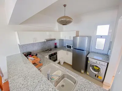 a kitchen with a sink and a refrigerator at Nayah Stays, Joubal Lagoons flowery apartment in Hurghada