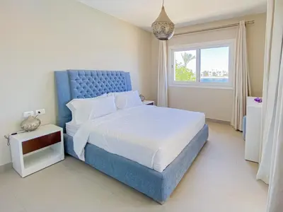 a bedroom with a blue bed and a window at Nayah Stays, Joubal Lagoons flowery apartment in Hurghada