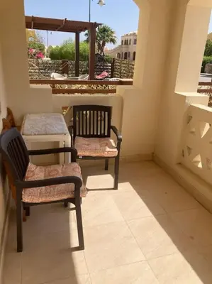 a balcony with two chairs and a table and a window at Lovely flat with balcony and shared pool in Hurghada