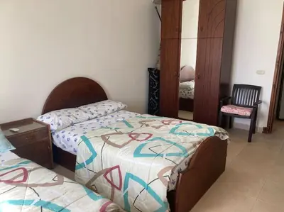 a bedroom with two twin beds and a chair at Lovely flat with balcony and shared pool in Hurghada