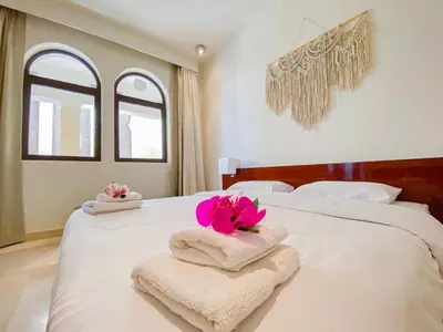 a white bed with towels and flowers on it at Nayah Stays, Ancient Sands Luxurious Pool Terrace Apartment in Hurghada