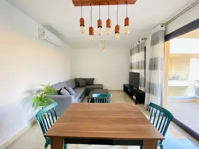 a living room with a wooden table and chairs at Sunny 1 BR Apt G cribs ElGouna with open View in Hurghada
