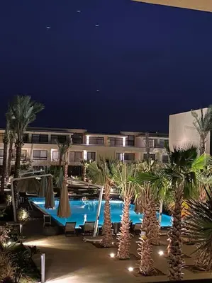 a resort with a pool with palm trees and umbrellas at Sunny 1 BR Apt G cribs ElGouna with open View in Hurghada