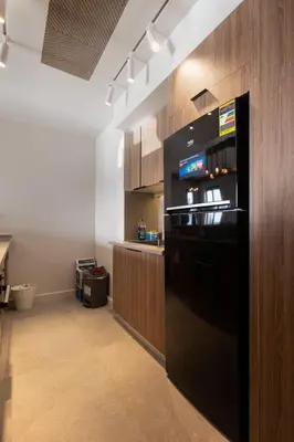 a kitchen with a black refrigerator and wooden cabinets at Fanadir Marina Front Penthouse with Pool in Hurghada