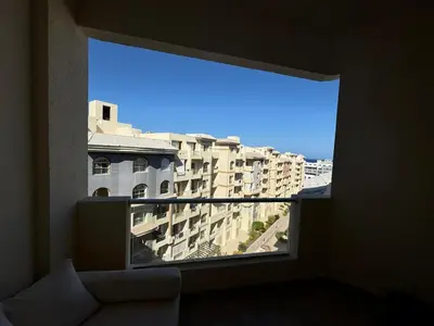 a large window with a view of a building at A one-bedroom apartment with a compact terrace in Hurghada
