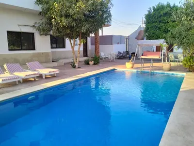 a blue swimming pool with chairs and a house at Villa River Nile in Al Qurnah