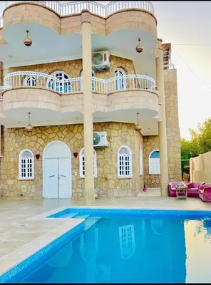 a house with a swimming pool in front of a building at Villa Nile Queen -guest house in Luxor