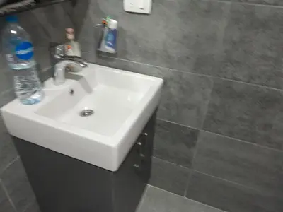 a bathroom with a white sink and a tiled wall at Spacious and modern one bed in hurhgarda in Hurghada