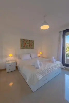a white bedroom with a large bed and a window at Chic 2 BR poolside Apartment at G-crib El Gouna in Hurghada
