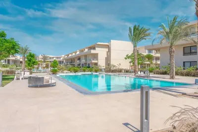 a swimming pool with palm trees in front of a building at Chic 2 BR poolside Apartment at G-crib El Gouna in Hurghada