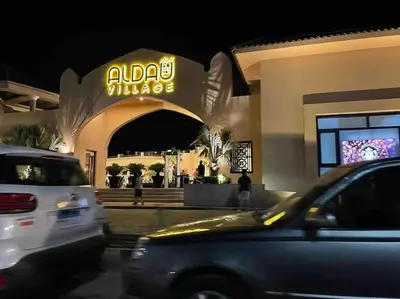 two cars parked in front of a building with a sign at Al Dau Heights in Hurghada