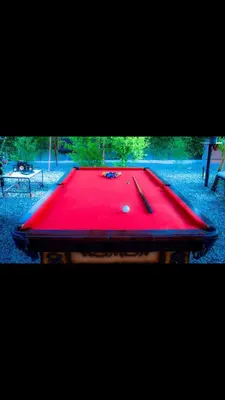 a red pool table with two cues on it at C and S park in Hurghada