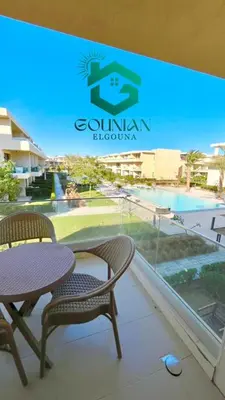 a balcony with a table and chairs and a swimming pool at ElGouna G-cribs One Bedroom in Hurghada
