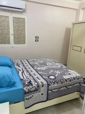 a bedroom with a bed with a blue blanket on it at Steven in Luxor